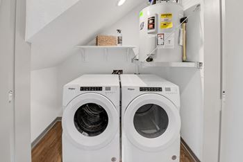 A washer and dryer in a laundry room with white walls and wooden floors